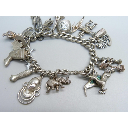 974 - A sterling silver charm bracelet with twenty charms, 66.8g