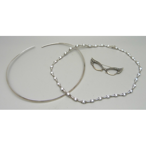 1028 - A silver and clear stone necklace, a torque silver necklace and a novelty silver brooch