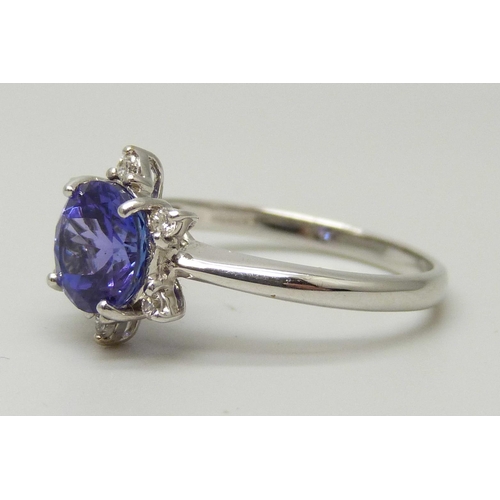 1035 - An 18ct white gold ring set with a round AAA grade tanzanite and six small round facet cut diamonds,... 