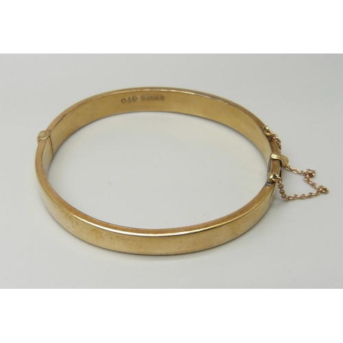 1042 - A 9ct yellow gold bangle with engraved front and safety chain, 9.9g