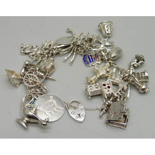 1112 - A silver charm bracelet with 26 charms, 63.9g