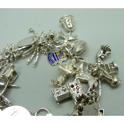 1112 - A silver charm bracelet with 26 charms, 63.9g