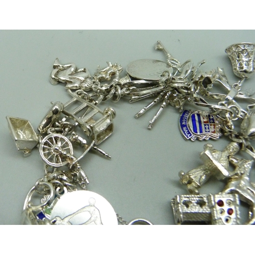 1112 - A silver charm bracelet with 26 charms, 63.9g