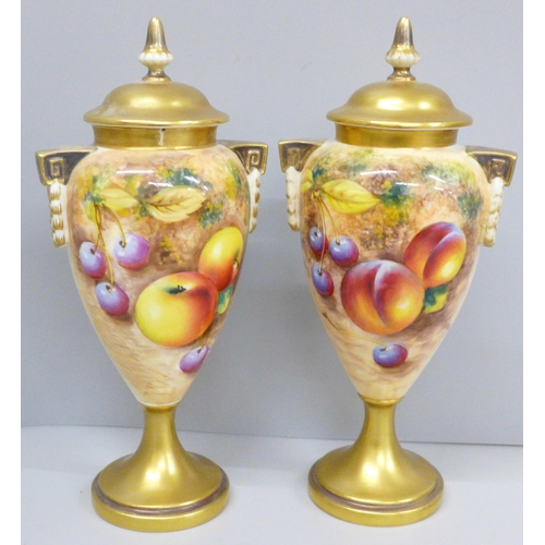A pair of Royal Worcester hand painted vases and covers, decorated with fruit, signed, one vase and cover a/f