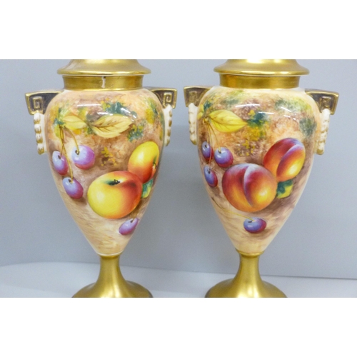 635 - A pair of Royal Worcester hand painted vases and covers, decorated with fruit, signed, one vase and ... 