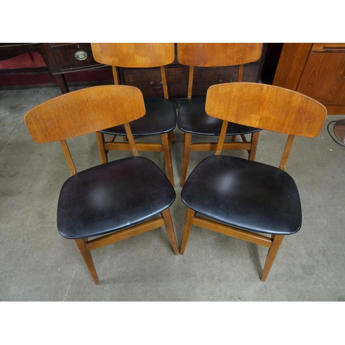 42 - A set of four teak and black vinyl chairs