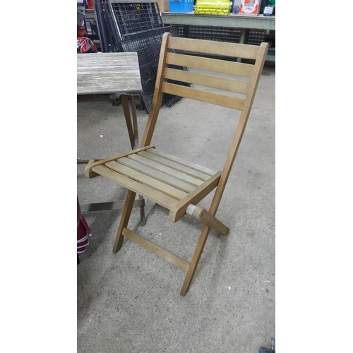 2383 - A folding wooden garden table and two chairs with parasol and seat cushions