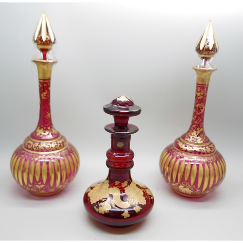 836 - A pair of early 20th Century cranberry glass bottle with lids and gilt detail and a ruby glass scent... 