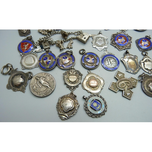 1063 - Twenty-three silver fob medals, some enamelled, 214g, four other fob medals and a charm bracelet