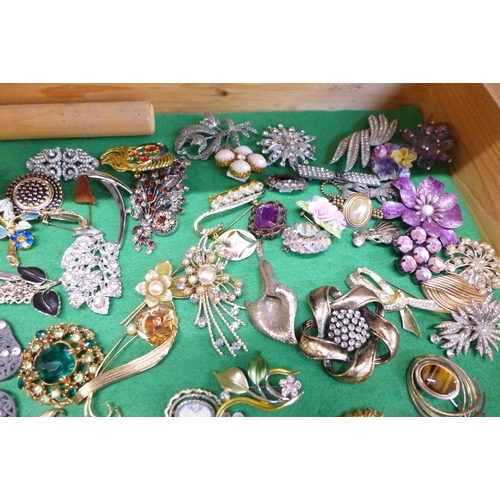 670 - A collection of costume jewellery and brooches in a glass and wooden display case