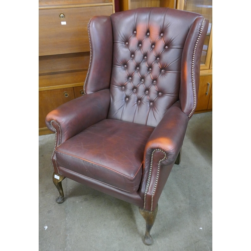 148 - A burgundy leather Chesterfield wingback armchair