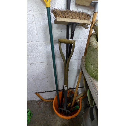 2231 - A quantity of garden tools including bow saw, rakes, brushes, a bucket, pitch fork, etc.