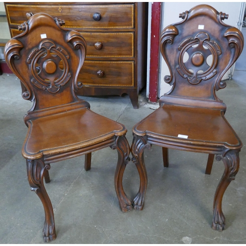 142 - A pair of Victorian carved mahogany hall chairs