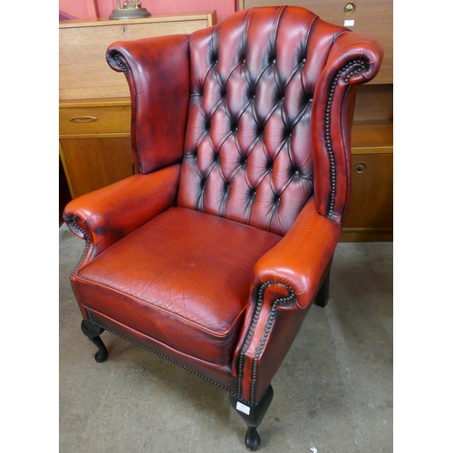 128 - An oxblood red leather Chesterfield wingback armchair