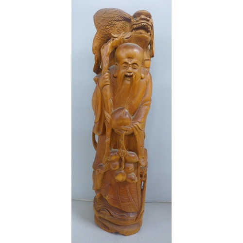 775 - An oriental wooden carving with bone inset eyes, 39.5cm