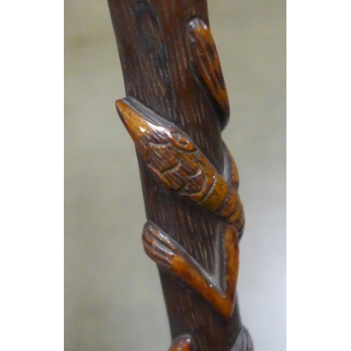 783 - A carved wooden walking stick, tropical hardwood, decorated with snakes, lizards, birds and mythical... 