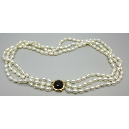 829A - A three strand freshwater pearl necklace with a gold clasp marked 14K 585, 75g