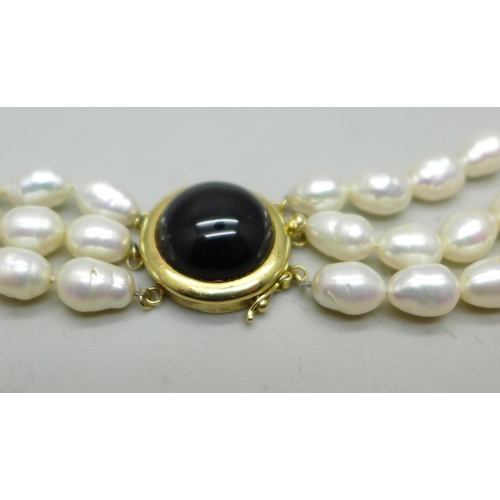 829A - A three strand freshwater pearl necklace with a gold clasp marked 14K 585, 75g