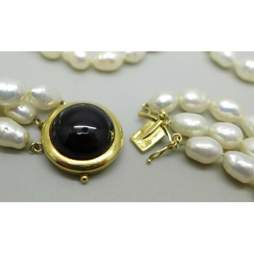 829A - A three strand freshwater pearl necklace with a gold clasp marked 14K 585, 75g