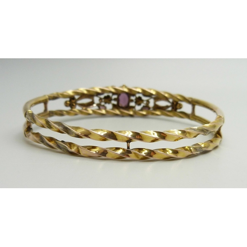 871 - A yellow metal bangle set with purple stones and seed pearls, a/f (one pearl missing, one stone repl... 