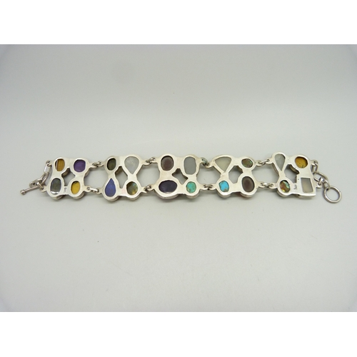 879 - A silver bracelet set with twenty gemstones including tiger's eye, amethyst, moonstone, labradorite ... 