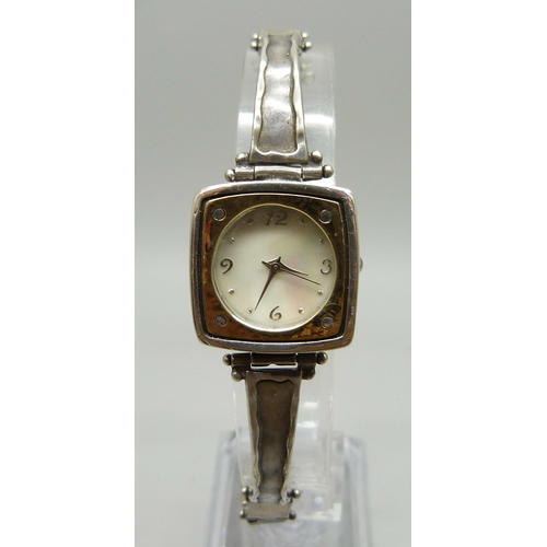 885 - A lady's silver wristwatch with hammered design bezel and strap, hallmarked on the clasp with plaque... 