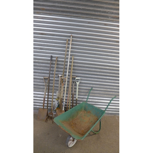 2199 - A metal wheelbarrow and a quantity of garden tools including spades, hoes, pitch forks and a rake et... 