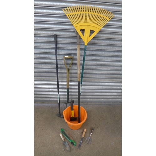 2245 - A quantity of garden tools including bow saw, rakes, brushes, a bucket, pitch fork, etc.