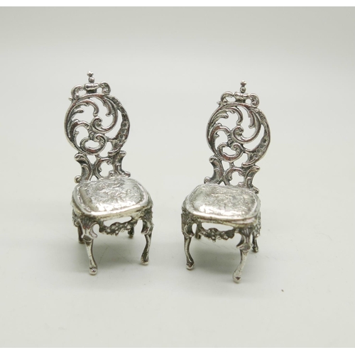 812 - A pair of silver miniature chairs with embossed cherub decoration, London 1897, 32g