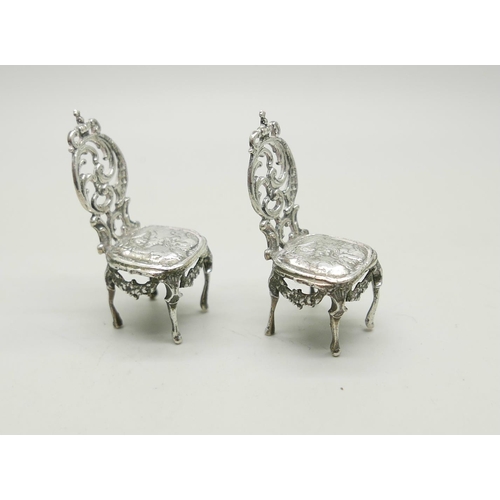 812 - A pair of silver miniature chairs with embossed cherub decoration, London 1897, 32g