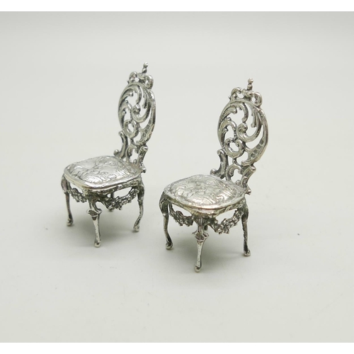 812 - A pair of silver miniature chairs with embossed cherub decoration, London 1897, 32g