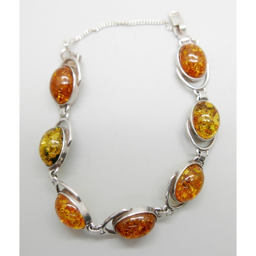 905 - A .830 silver Modernist style amber pendant, a silver and amber bracelet and another amber bracelet