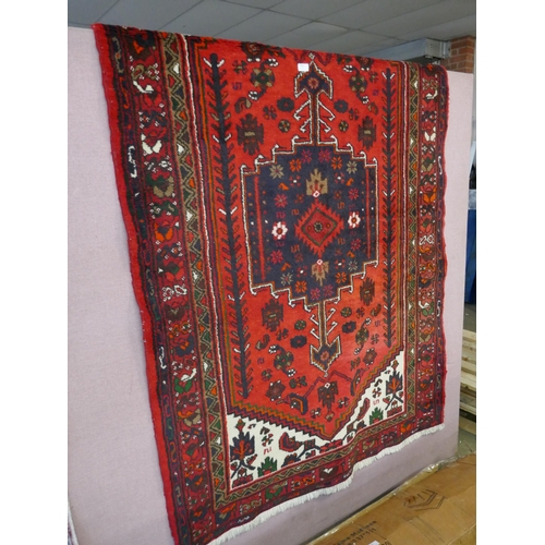 1340 - A Rich Red ground handwoven full wool pile Persian village rug (195x130cm)