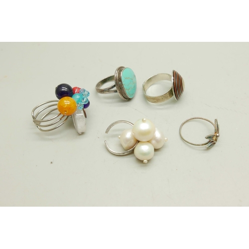 1002 - Three silver plated rings and two rings stamped 925 including a turquoise example (stone chipped)