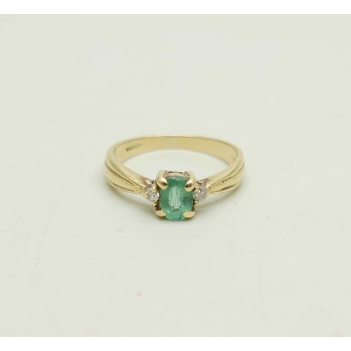 1023 - A 9ct gold ring set with an emerald and two small diamonds, 1.9g, J/K