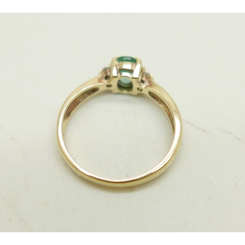 1023 - A 9ct gold ring set with an emerald and two small diamonds, 1.9g, J/K