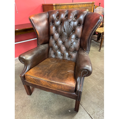 153 - A chestnut brown leather wingback armchair