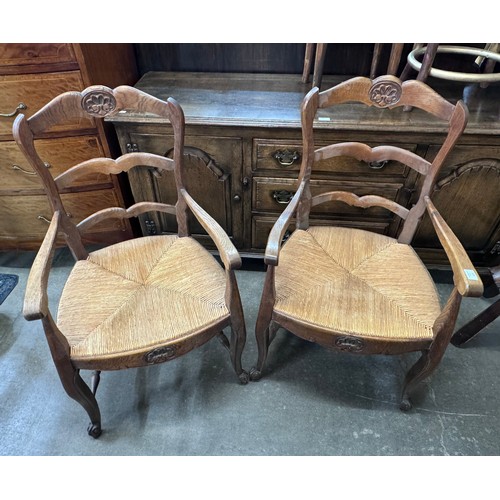 223 - A pair of French carved oak rush seated elbow chairs