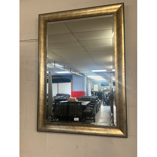 1525 - A large bevelled edge wall mirror in a black and gold frame