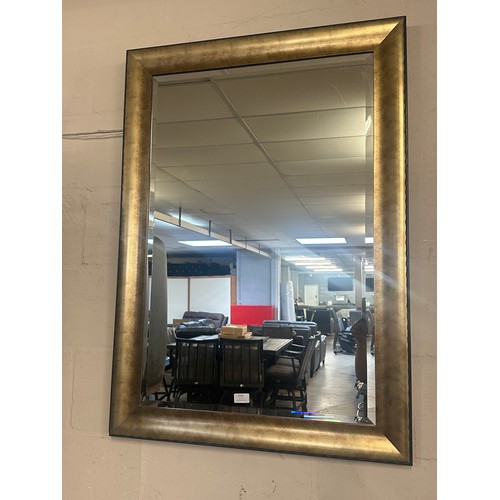 1525 - A large bevelled edge wall mirror in a black and gold frame