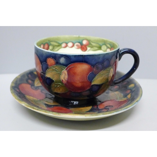 633B - A Moorcroft pomegranate cup and saucer, hairline crack to cup