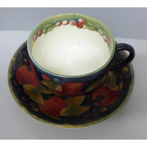 633B - A Moorcroft pomegranate cup and saucer, hairline crack to cup