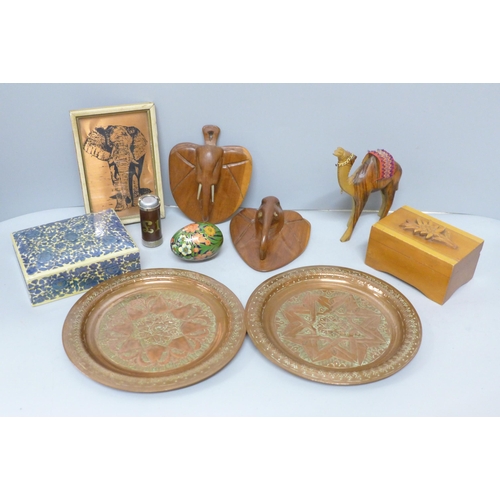 792 - Two Eastern metal trays, two carved elephant plaques, a musical box, a carved camel figure, a decora... 