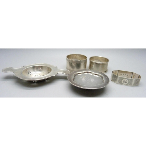 814 - Three silver napkin rings, a silver tea strainer and a Victorian silver miniature dish, 121g