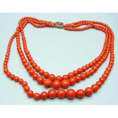 961 - A three strand red coral necklace with white metal clasp, requires re-stringing