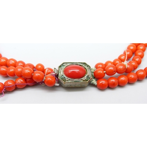 961 - A three strand red coral necklace with white metal clasp, requires re-stringing