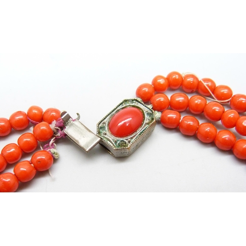 961 - A three strand red coral necklace with white metal clasp, requires re-stringing