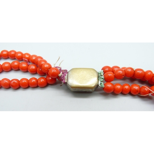 961 - A three strand red coral necklace with white metal clasp, requires re-stringing