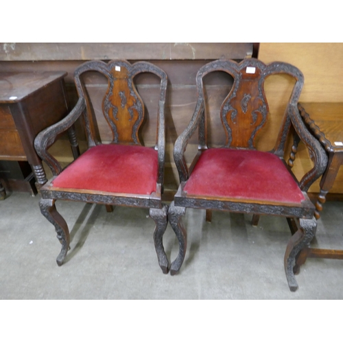 151 - A pair of early 20th Century Burmese carved hardwood elbow chairs