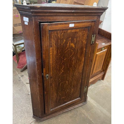 191 - A George III oak splay front wall hanging corner cupboard